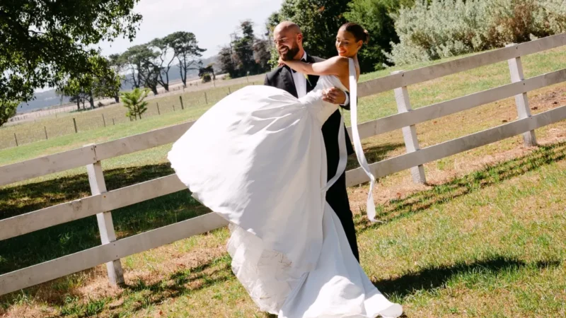 A bride showing off her wedding smile in a white wedding dress, she is held by the groom