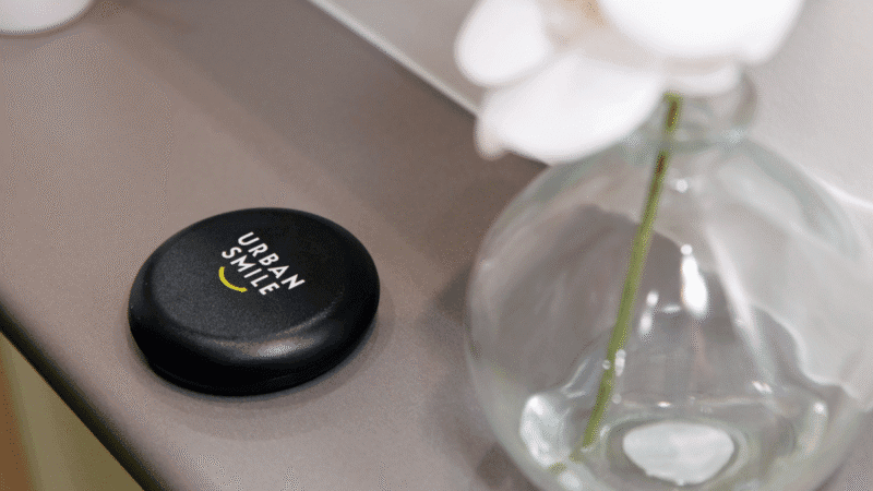 Urban Smile clear aligner case sitting on a bench next to white flowers