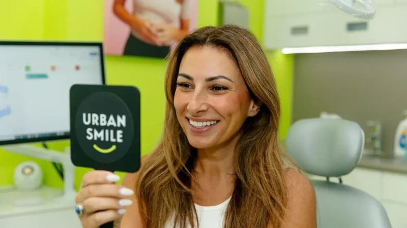 Urban Smile patient Zoe looks at her smile in the mirror after clear aligner treatment