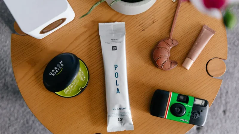 POLA Night At-Home Teeth Whitening packet on a table with Urban Smile retainer case, disposable camera, lip balm and keys