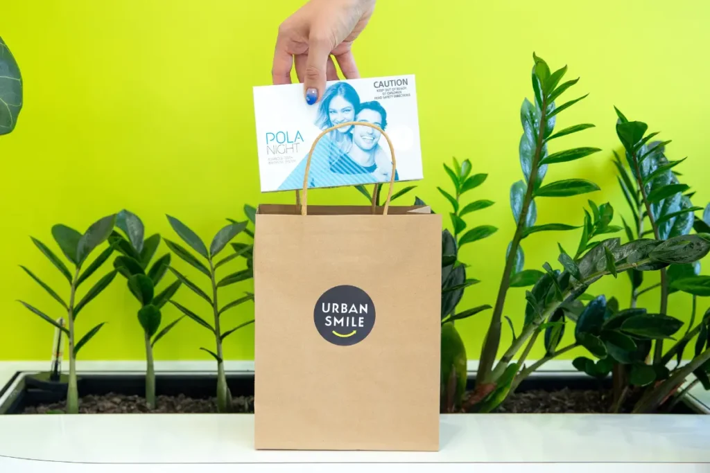 Hand putting Pola Night teeth whitening kit into an Urban Smile shopping bag