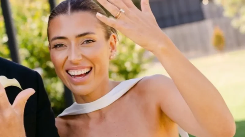 Bride showing off her wedding smile and holding her ring up to the camera