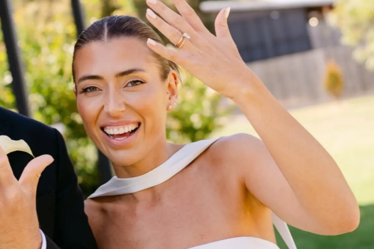 Bride showing off her wedding smile and holding her ring up to the camera
